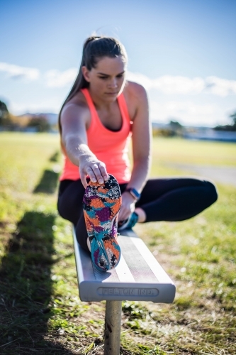 Female stretching on bench - Australian Stock Image