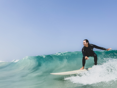 Female surfer in steamer wetsuit surfing clean green wave - Australian Stock Image