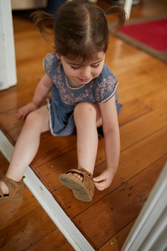 Female toddler girl putting shoes on - Australian Stock Image