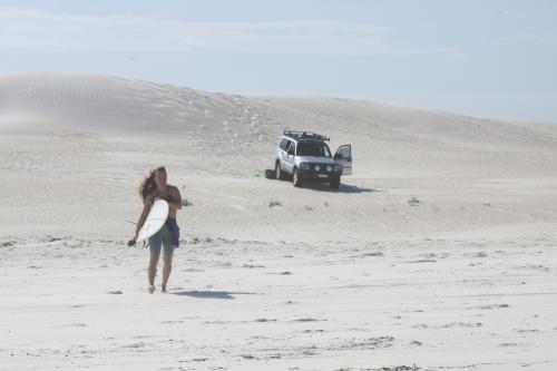 Female walking on sand dunes to head out for a surf