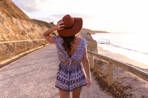 Female walks towards beach at sunset