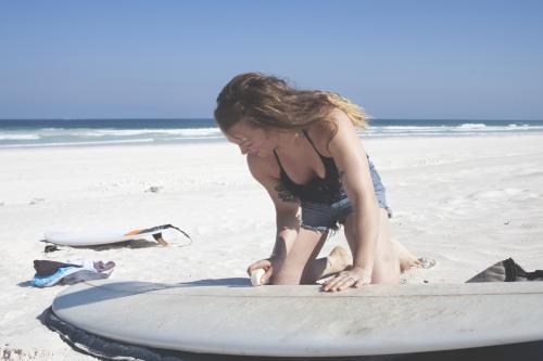 Female waxing surf board pre-surf