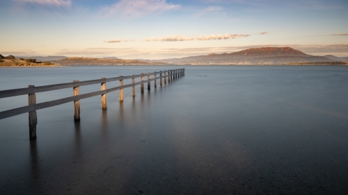 Fence at high tide at Mortimer Bay and Mount Wellington in the background, Tasmania - Australian Stock Image