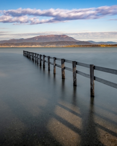 Fence at high tide at Mortimer Bay and Mount Wellington in the background, Tasmania - Australian Stock Image