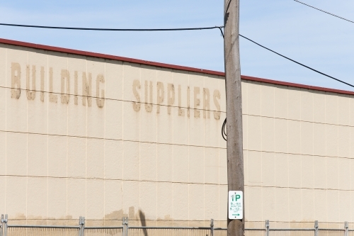 Fenced off wall of old building with faded signage - Australian Stock Image