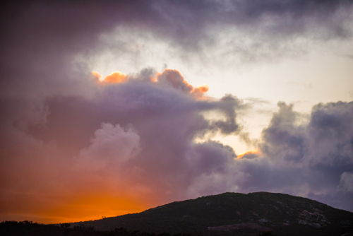 Fiery sunset clouds above a darkened hillside - Australian Stock Image