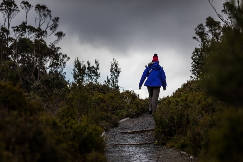 figure hiking towards stormy clouds