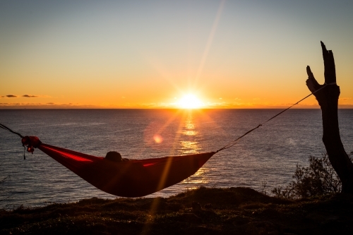 Figure in a hammock overlooking the ocean - Australian Stock Image