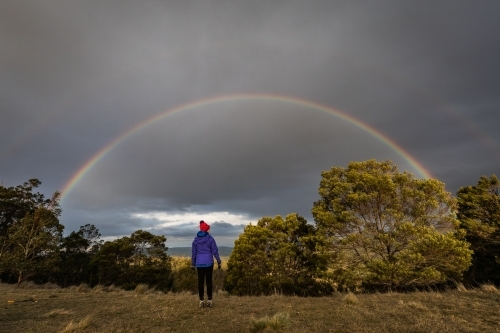 figure in nature looking towards a rainbow - Australian Stock Image