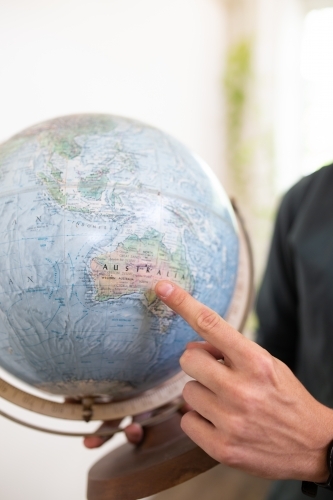 Finger pointing to map of Australia on round world globe - Australian Stock Image
