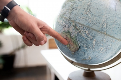 Finger pointing to map of Australia on round world globe - Australian Stock Image