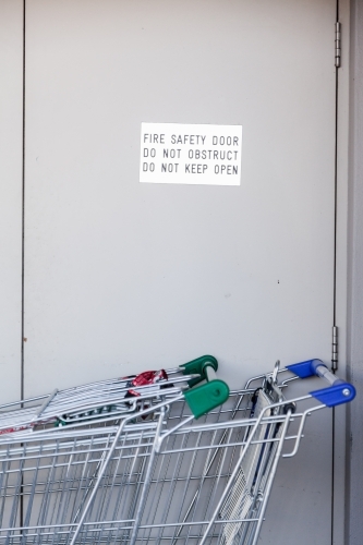 Fire safety door do not obstruct, do not keep open sign with trollies blocking door - Australian Stock Image