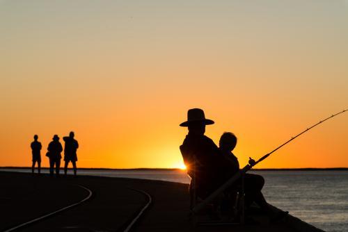 Fisherman and people silhouetted in sunset - Australian Stock Image