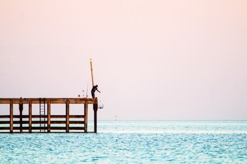 Fisherman lowering a crab pot from jetty in Wallaroo - Australian Stock Image