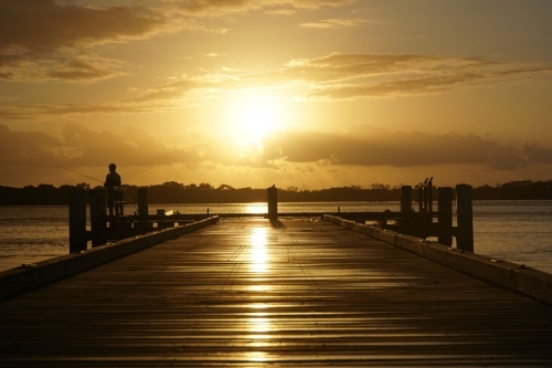 Fisherman on jetty at sunrise - Australian Stock Image