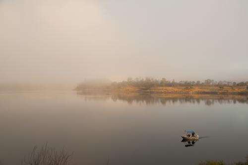 Fishermen in a tinny on a misty lake