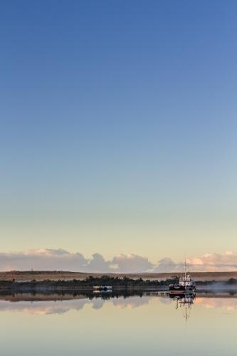 Fishing boat on calm waters with reflection - Australian Stock Image