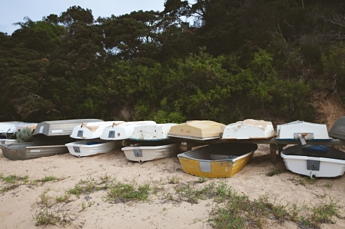 Fishing boats stacked on dry land on a beach at mornington - Australian Stock Image
