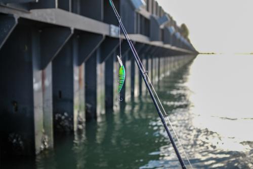 Fishing lure hanging from fishing rod - Australian Stock Image
