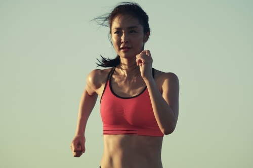 Fit Asian woman running for morning exercise - Australian Stock Image
