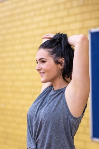fit girl doing stretching exercise before playing sport - Australian Stock Image