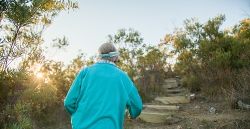 Fit granny hiking up mountain steps in the early morning - Australian Stock Image