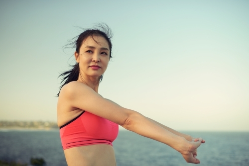 Fit woman stretching outside for morning exercise - Australian Stock Image