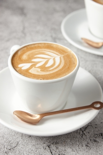 Flat white on saucer with spoon - Australian Stock Image