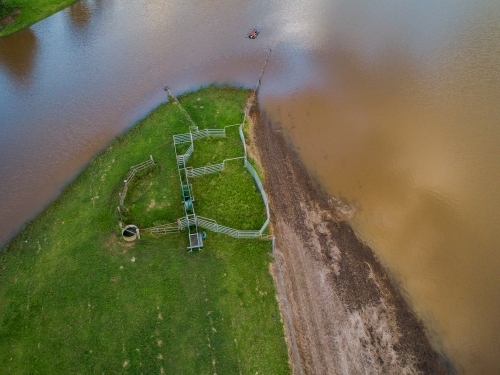 Flood waters creeping up towards cattle yard on farm - Australian Stock Image