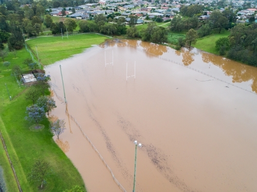 Flooded sports oval covered in brown floodwater
