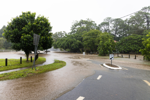 Flooding across a street in suburban Brisbane during a major rain event - Australian Stock Image