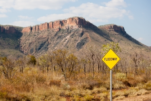 Floodway sign on outback road with mountains in background