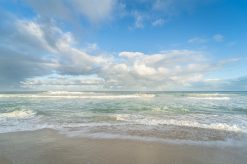 Foamy shore break waves on beach under soft clouds at Scarborough Beach, Perth, Western Australia - Australian Stock Image
