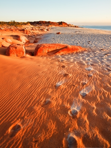 Footprints leading through sand at a remote beach