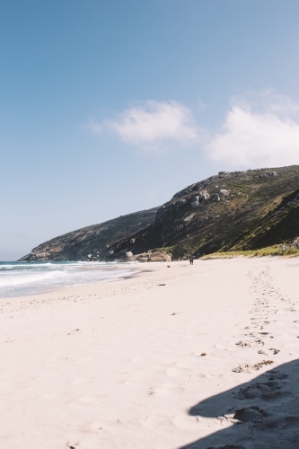 Footprints on secluded beach surrounded by hills - Australian Stock Image