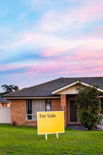 For Sale sign beside house at dusk with bright colours - Australian Stock Image