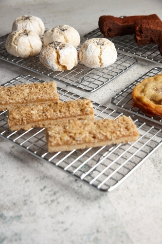 Four baking racks of baked treats at cafe - Australian Stock Image