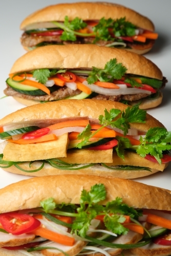 Four banh mi lined up on blank background - Australian Stock Image