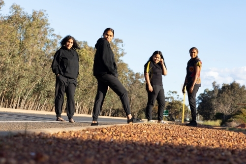 four teenagers dressed in black standing on the edge of a road - Australian Stock Image