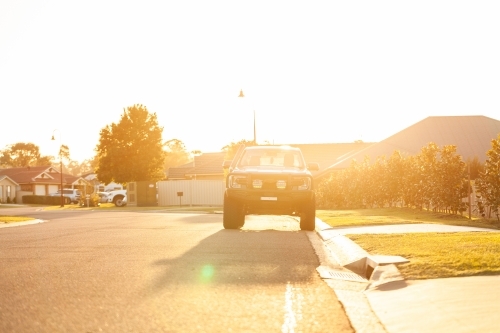 Four wheel drive car parked on the side of a suburban road at sunset - Australian Stock Image