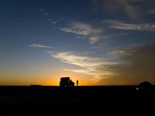 Four wheel drive vehicle and a person silhouetted against the sunset - Australian Stock Image