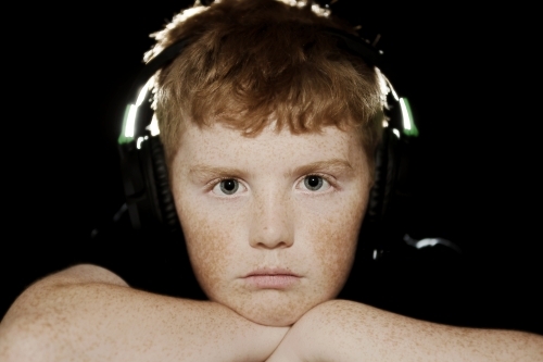 freckled teenage boy looking at cameras with headphones on