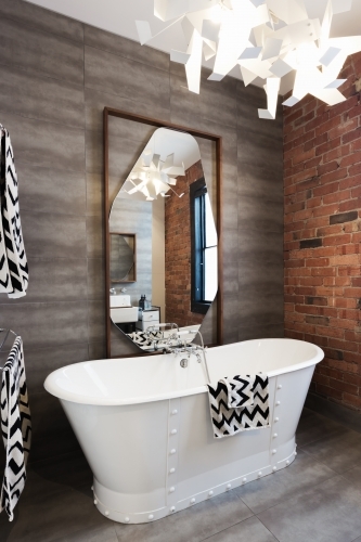 Freestanding vintage style white bath tub in renovated warehouse apartment - Australian Stock Image