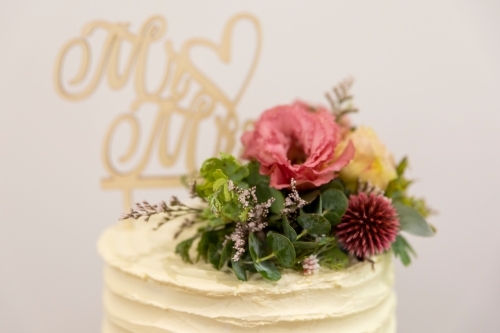 fresh flowers on top of simple wedding cake - Australian Stock Image