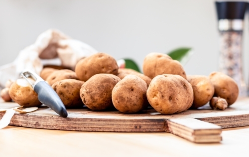 Fresh unpeeled potatoes on a chopping board with a shallow depth of field