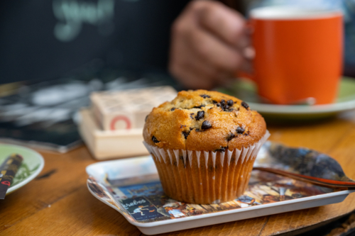 Freshly baked muffin with chocolate chips perched on a decorative plate - Australian Stock Image