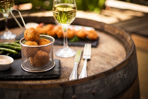 Fried cheese balls served in metal basket on a black plate with cream sauce and utensils on the side - Australian Stock Image