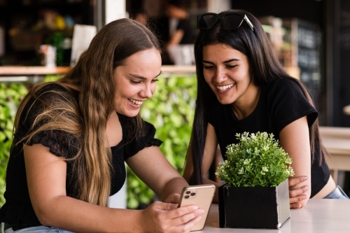 friends laughing at something on their mobile phone - Australian Stock Image