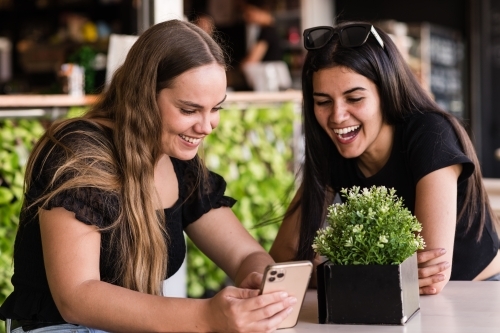 friends laughing at something on their mobile phone - Australian Stock Image
