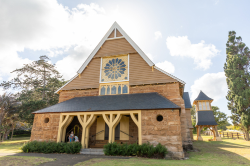 Front of historic stone chapel on green lawn with blue sky - Australian Stock Image